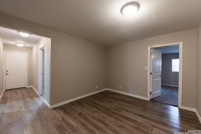 spare room with dark hardwood / wood-style floors and a textured ceiling