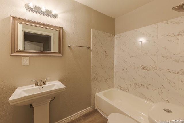 full bathroom with toilet, tiled shower / bath, hardwood / wood-style floors, and sink