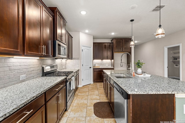 kitchen with stainless steel appliances, a center island with sink, sink, and backsplash