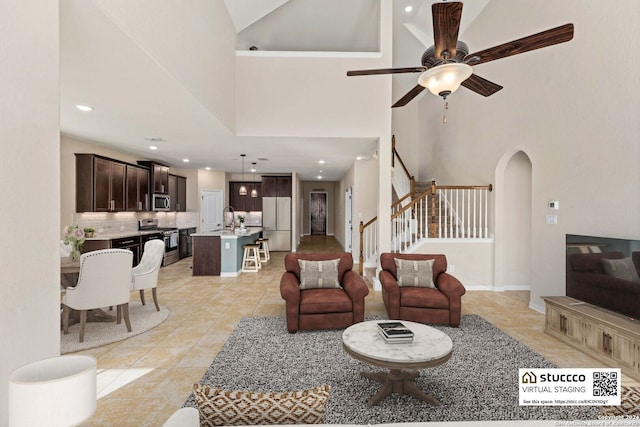 living room with light tile patterned floors, sink, high vaulted ceiling, and ceiling fan