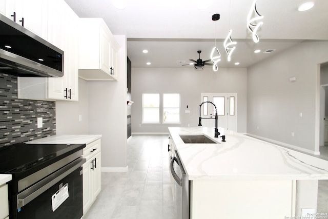 kitchen featuring sink, white cabinetry, stainless steel appliances, light stone counters, and a kitchen island with sink