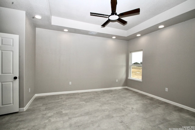 unfurnished room with ceiling fan and a raised ceiling