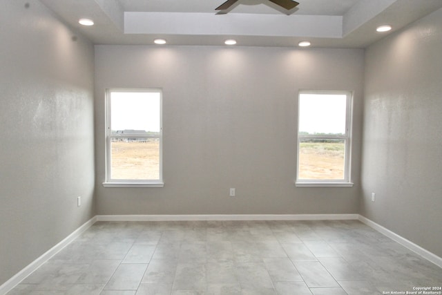 unfurnished room featuring ceiling fan and a raised ceiling