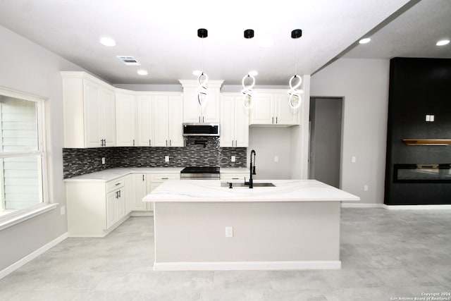 kitchen with white cabinets, an island with sink, light stone countertops, stainless steel appliances, and sink