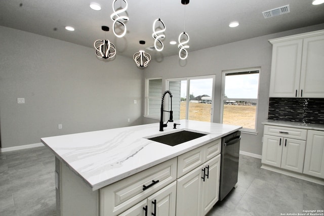 kitchen with stainless steel dishwasher, white cabinets, sink, and an island with sink