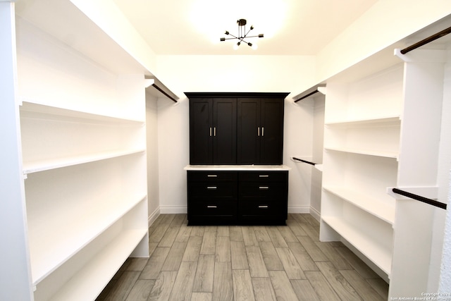 walk in closet with a chandelier and light wood-type flooring