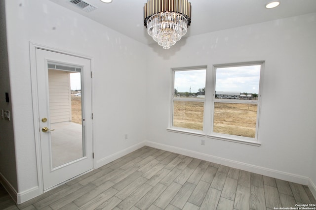 unfurnished dining area featuring an inviting chandelier and light wood-type flooring