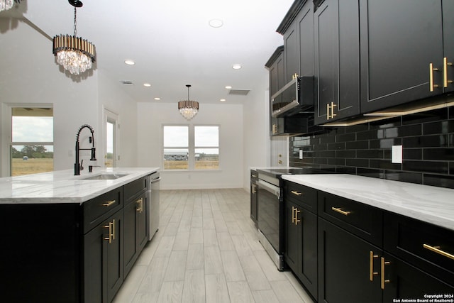 kitchen with sink, decorative light fixtures, appliances with stainless steel finishes, a notable chandelier, and backsplash