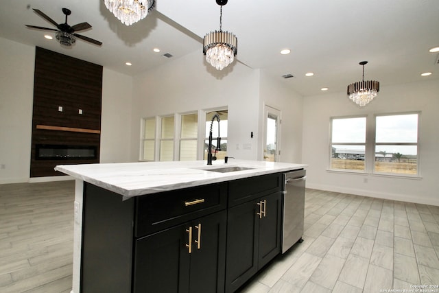 kitchen with pendant lighting, sink, dishwasher, a large fireplace, and a center island with sink