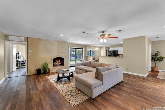 living room with a brick fireplace, hardwood / wood-style flooring, and ceiling fan