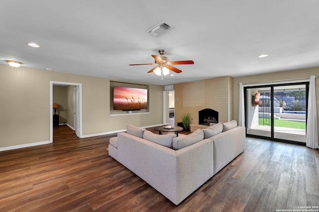 living room with dark wood-type flooring, a fireplace, and ceiling fan