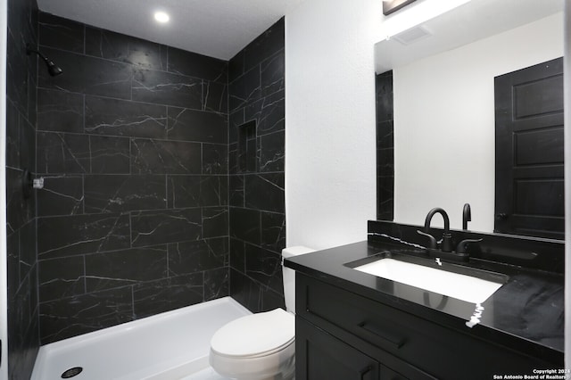 bathroom featuring toilet, vanity, and a tile shower