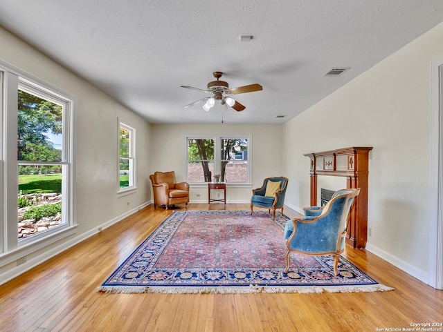 sitting room featuring light hardwood / wood-style flooring, a textured ceiling, and ceiling fan