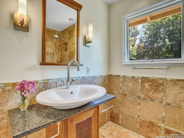 bathroom featuring vanity, tiled shower, and tile walls