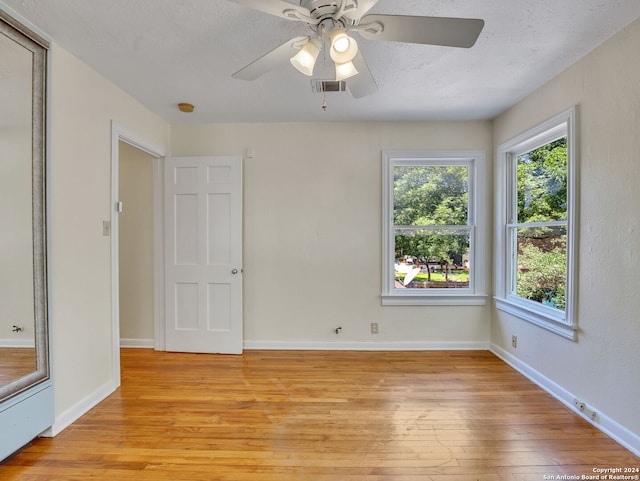 empty room with a textured ceiling, light hardwood / wood-style floors, and ceiling fan