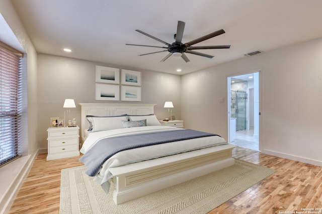 bedroom featuring ensuite bathroom, ceiling fan, multiple windows, and light wood-type flooring