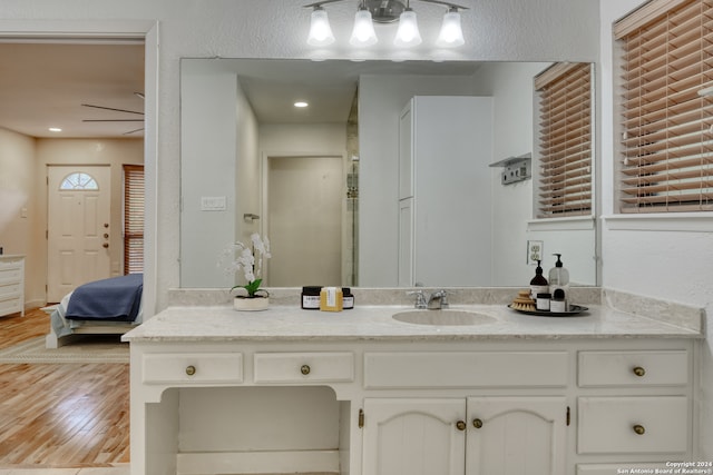 bathroom with hardwood / wood-style flooring, ceiling fan, and vanity