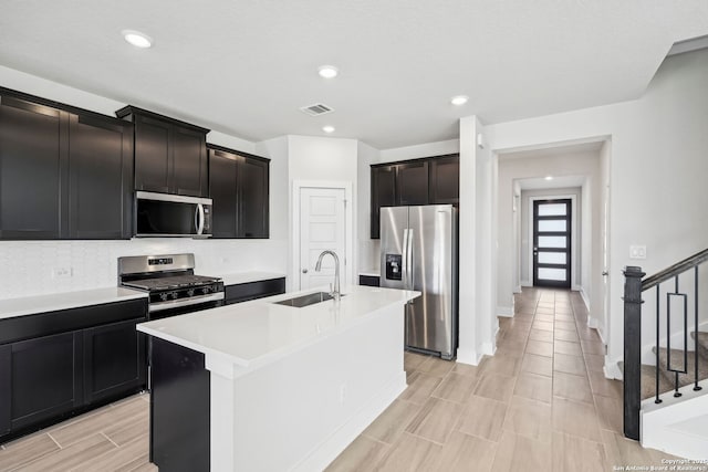 kitchen with sink, stainless steel appliances, and a center island with sink