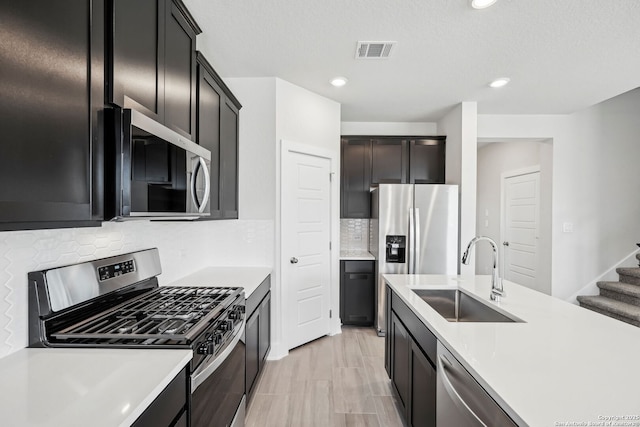 kitchen with appliances with stainless steel finishes, sink, a textured ceiling, and backsplash