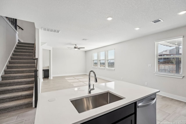 kitchen with dishwasher, sink, ceiling fan, and a textured ceiling