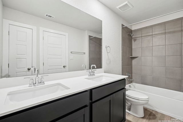 full bathroom featuring tiled shower / bath, hardwood / wood-style floors, vanity, and toilet