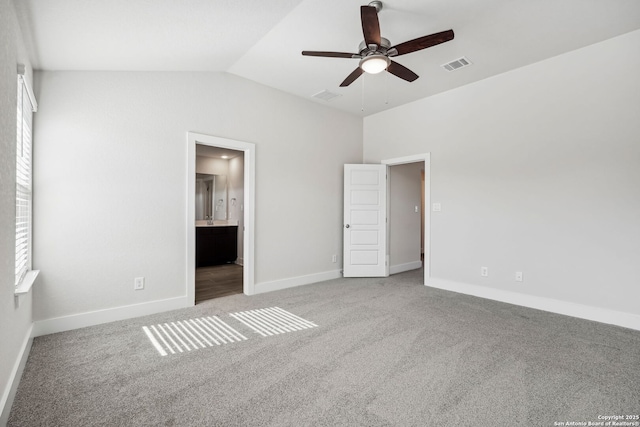 unfurnished bedroom featuring multiple windows, vaulted ceiling, ceiling fan, and ensuite bathroom