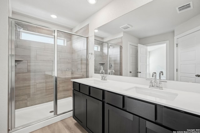 bathroom with wood-type flooring, an enclosed shower, and vanity