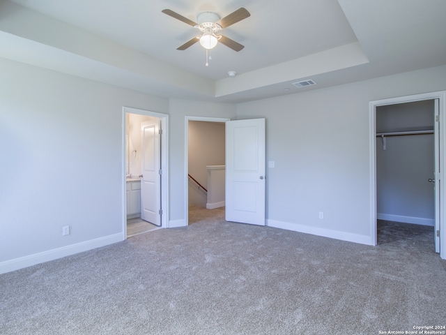 unfurnished bedroom featuring a closet, a walk in closet, ensuite bath, and ceiling fan