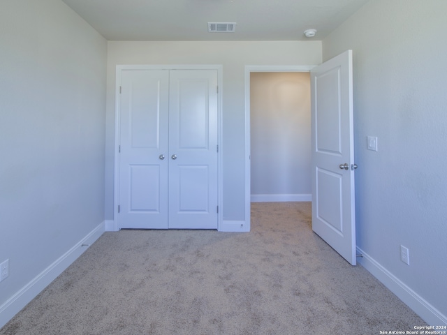 unfurnished bedroom featuring light carpet and a closet