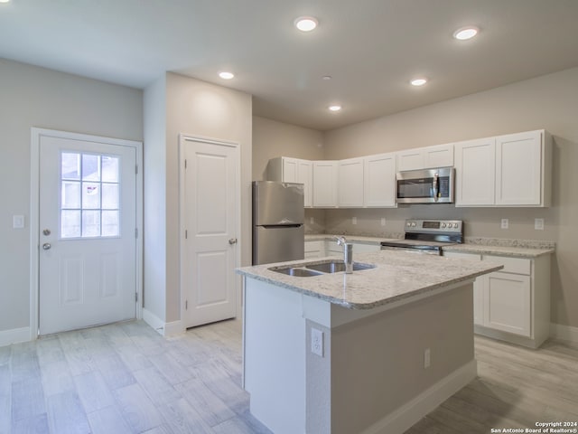 kitchen with sink, white cabinets, stainless steel appliances, and an island with sink