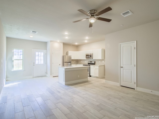 kitchen featuring a kitchen island with sink, white cabinets, appliances with stainless steel finishes, light hardwood / wood-style floors, and ceiling fan