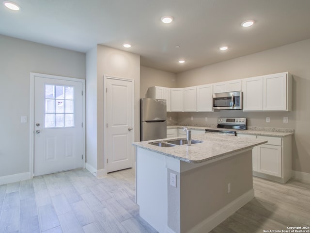 kitchen with sink, appliances with stainless steel finishes, white cabinetry, and an island with sink