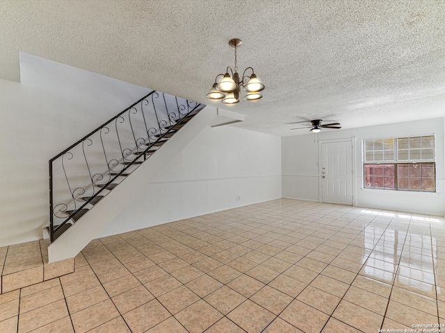 interior space with a textured ceiling, ceiling fan with notable chandelier, and light tile patterned floors