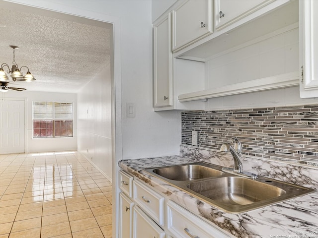 kitchen featuring backsplash, sink, light tile patterned flooring, white cabinets, and a textured ceiling