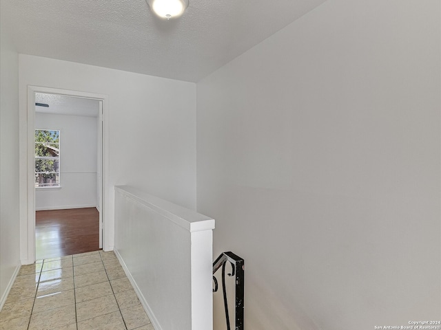 hall featuring a textured ceiling and light tile patterned flooring