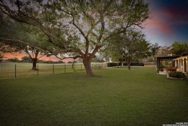 yard at dusk with a rural view and a pergola