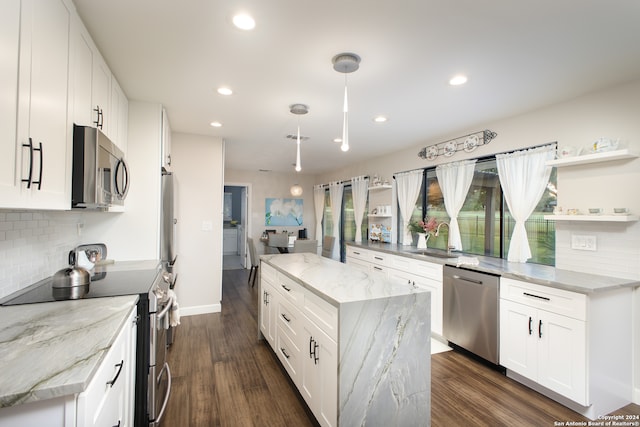 kitchen with light stone countertops, appliances with stainless steel finishes, a kitchen island, dark hardwood / wood-style flooring, and white cabinets