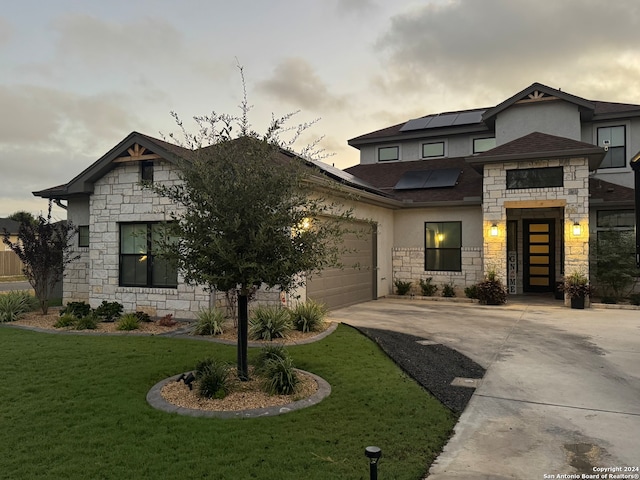 view of front facade featuring a yard, a garage, and solar panels