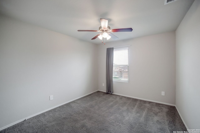 empty room featuring ceiling fan and dark carpet