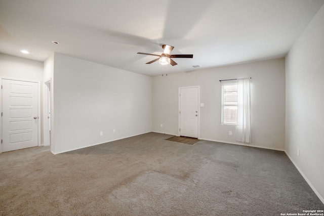 unfurnished room with ceiling fan and dark carpet