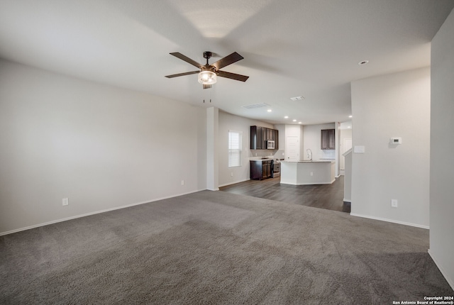 unfurnished living room with dark hardwood / wood-style floors, ceiling fan, and sink