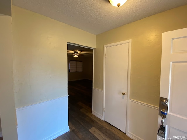 corridor featuring a textured ceiling and dark hardwood / wood-style flooring