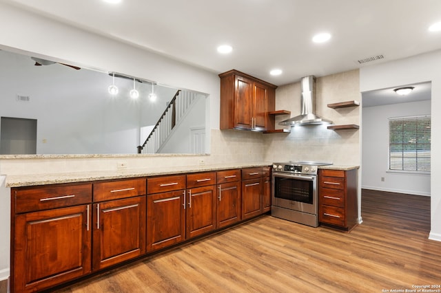 kitchen with decorative backsplash, wall chimney range hood, stainless steel electric stove, and light hardwood / wood-style floors