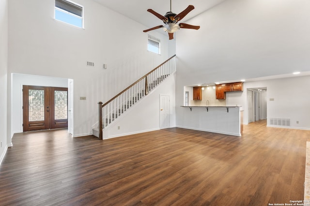 unfurnished living room featuring french doors, dark hardwood / wood-style flooring, plenty of natural light, and a high ceiling