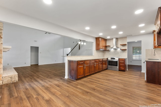 kitchen with sink, dark hardwood / wood-style flooring, kitchen peninsula, stainless steel electric stove, and wall chimney exhaust hood