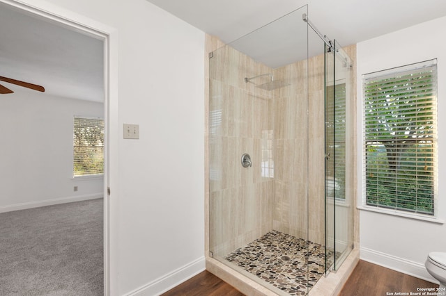 bathroom featuring a shower with door, toilet, ceiling fan, and hardwood / wood-style floors