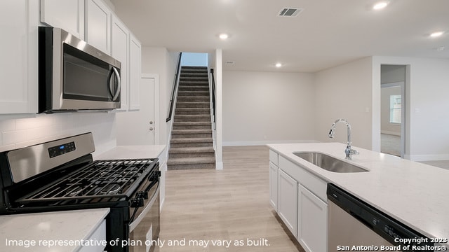 kitchen with appliances with stainless steel finishes, a sink, light wood-style floors, light countertops, and recessed lighting