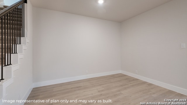 unfurnished room featuring stairs, light wood-style floors, and baseboards
