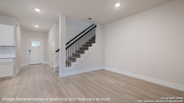 entryway with light wood-type flooring, stairway, baseboards, and recessed lighting