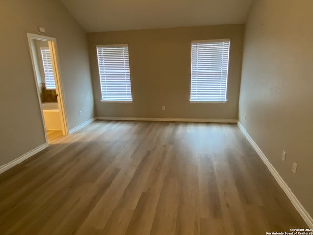 unfurnished room with light hardwood / wood-style floors and vaulted ceiling